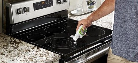 A person cleaning a glass stovetop with affresh.