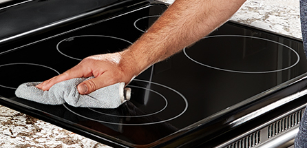 A person cleaning a cooktop with affresh® cooktop cleaner.