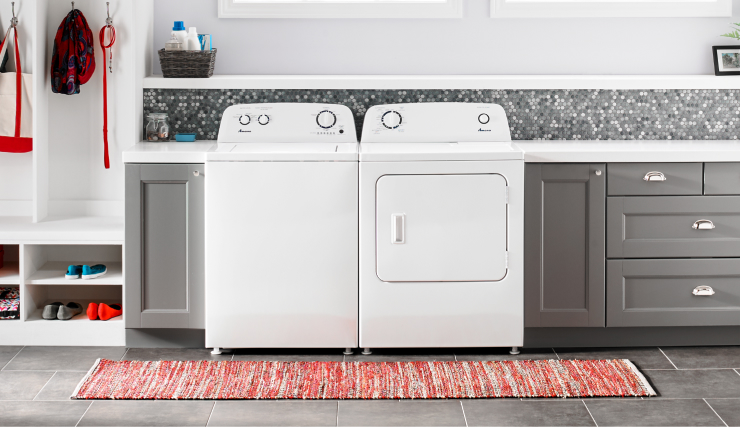 White Amana® top load washer and dryer in a laundry room with gray cabinets