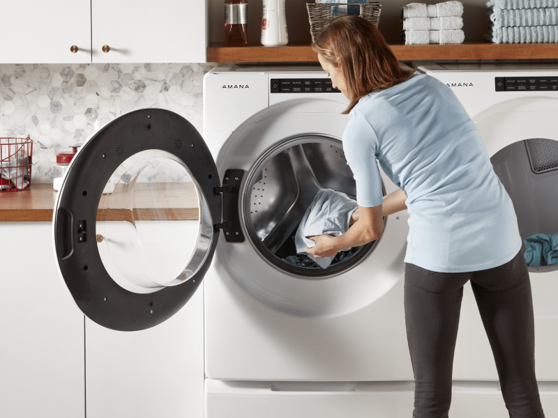 Woman loading clothes into a front loading washer