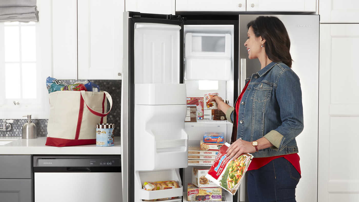  Person putting food in Amana® side-by-side refrigerator
