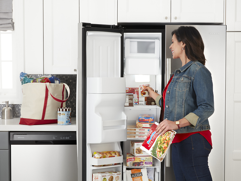 Person putting food in Amana® side-by-side refrigerator