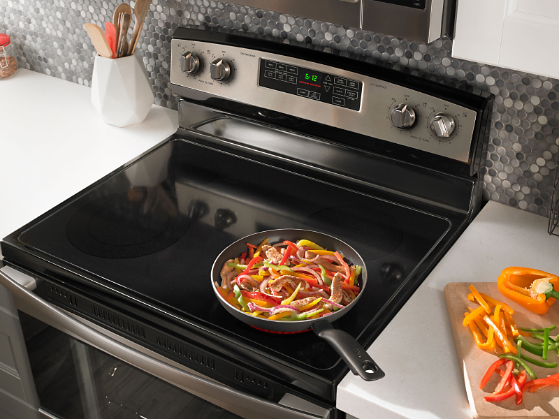 Food cooking on stovetop of stainless steel Amana® range