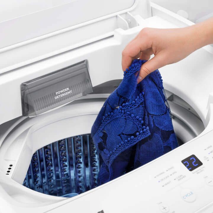 Person putting clothes into washer Person putting clothes into washer