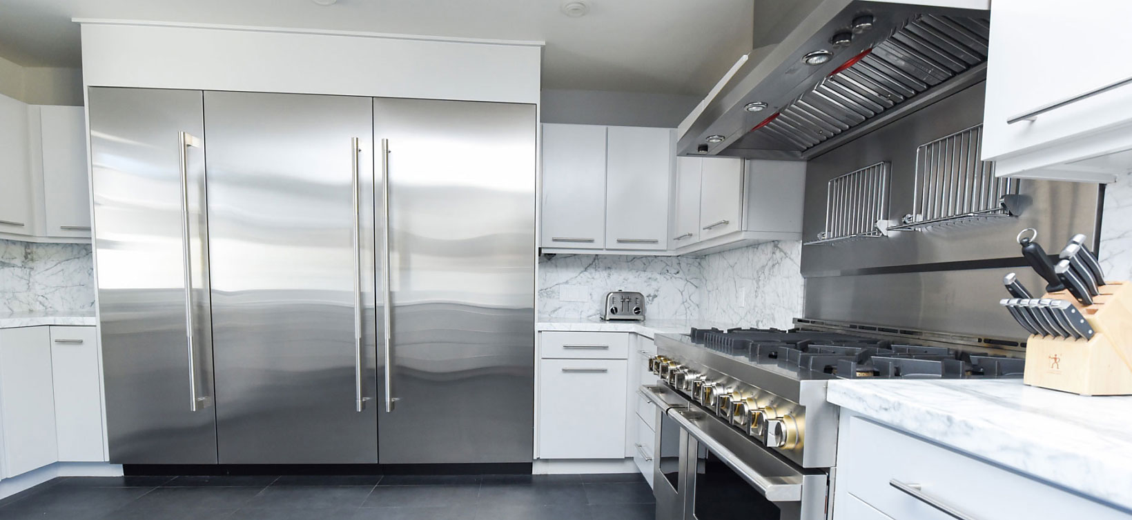 JennAir column refrigerators and freezers in a bright modern kitchen with a JennAir range and ventilation system. 