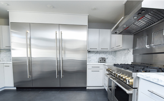 JennAir column refrigerators and freezers in a bright modern kitchen with a JennAir range and ventilation system. 