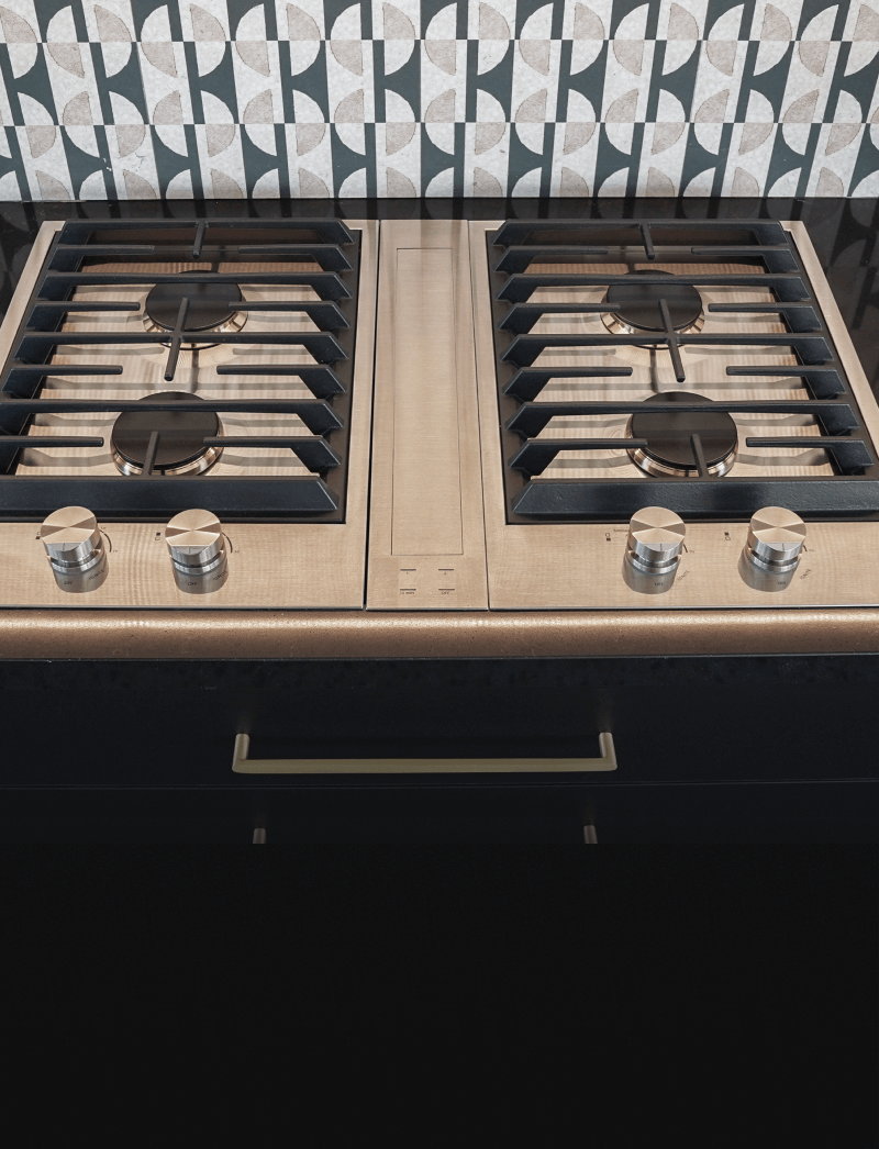 A close up on a pair of JennAir® Custom Cooktops with a Downdraft Ventilation Strip in the center.