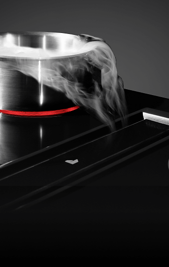  A JennAir® Downdraft Electric Cooktop pulling steam into the vent.