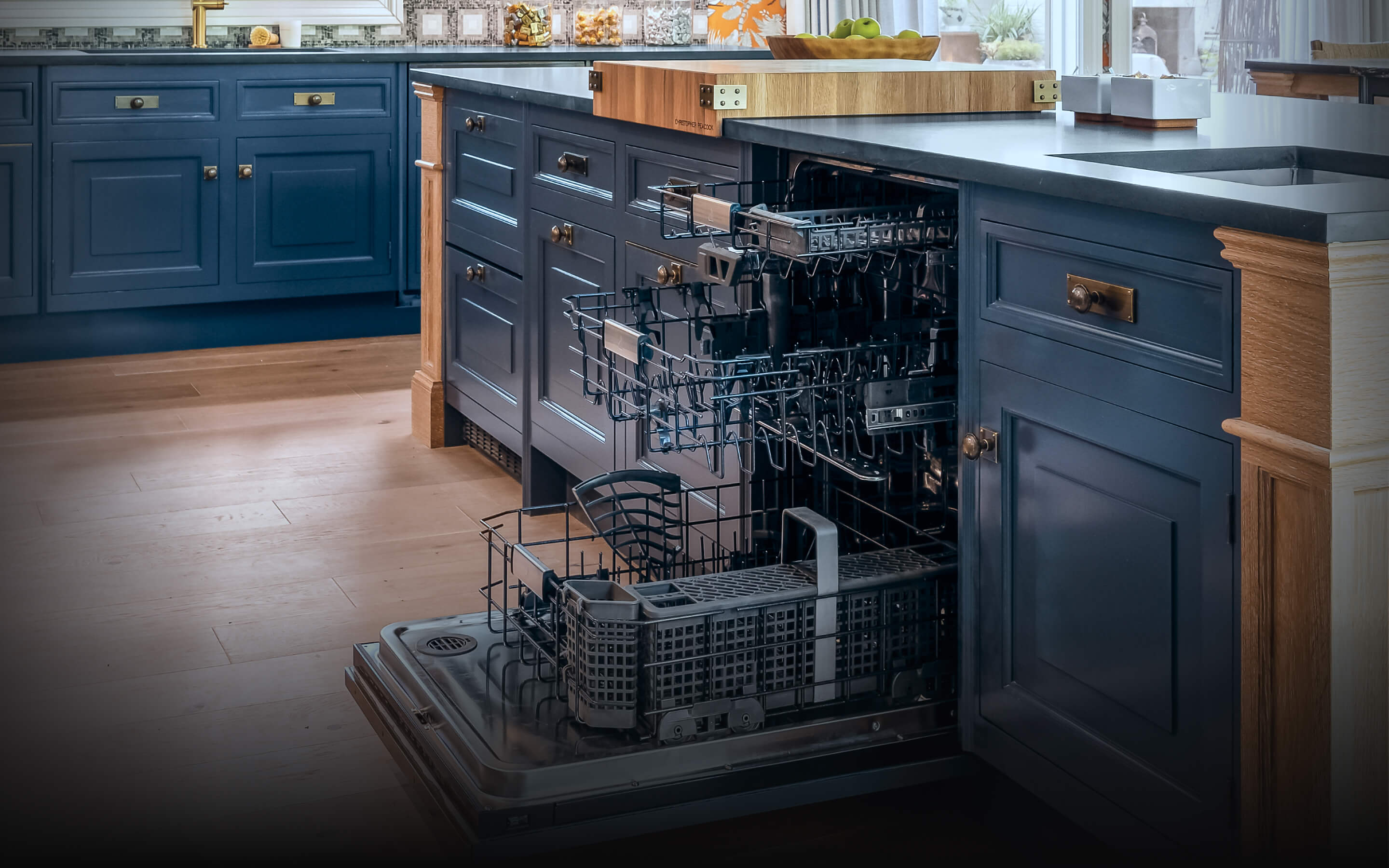 An open JennAir® Panel-Ready Dishwasher in a kitchen with blue cabinets.