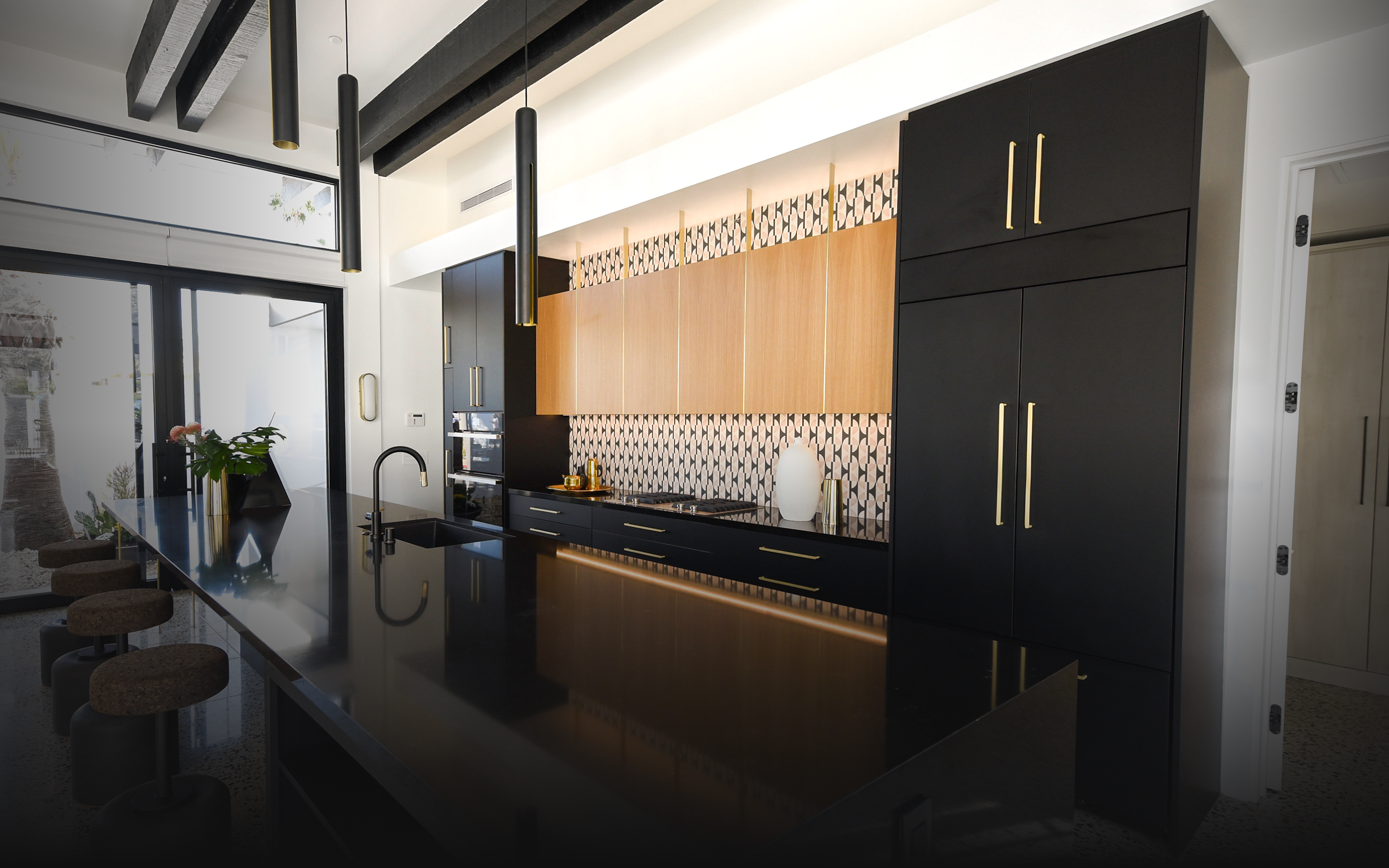  A black and gold modern kitchen featuring JennAir® appliances.