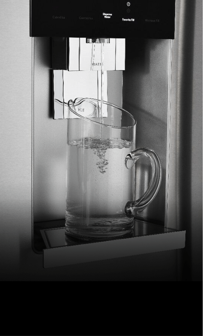 The front of a JennAir® built-in refrigerator, showing water being poured into a glass from the external dispenser.