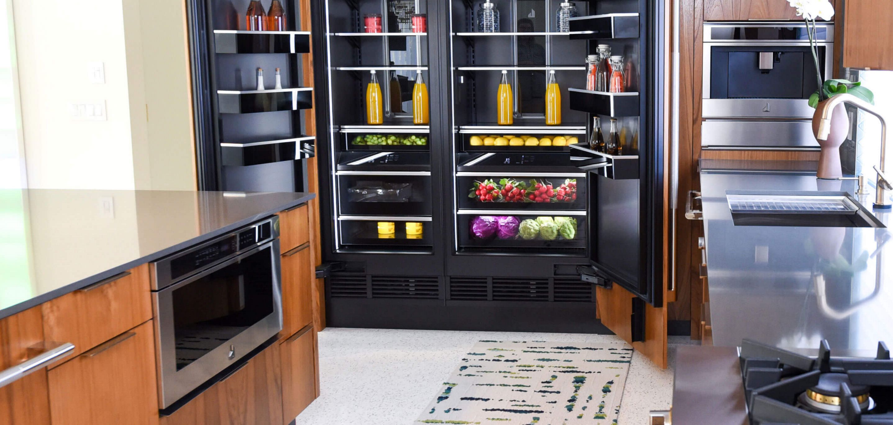 A modern JennAir® kitchen in a home, with a stocked open refrigerator.