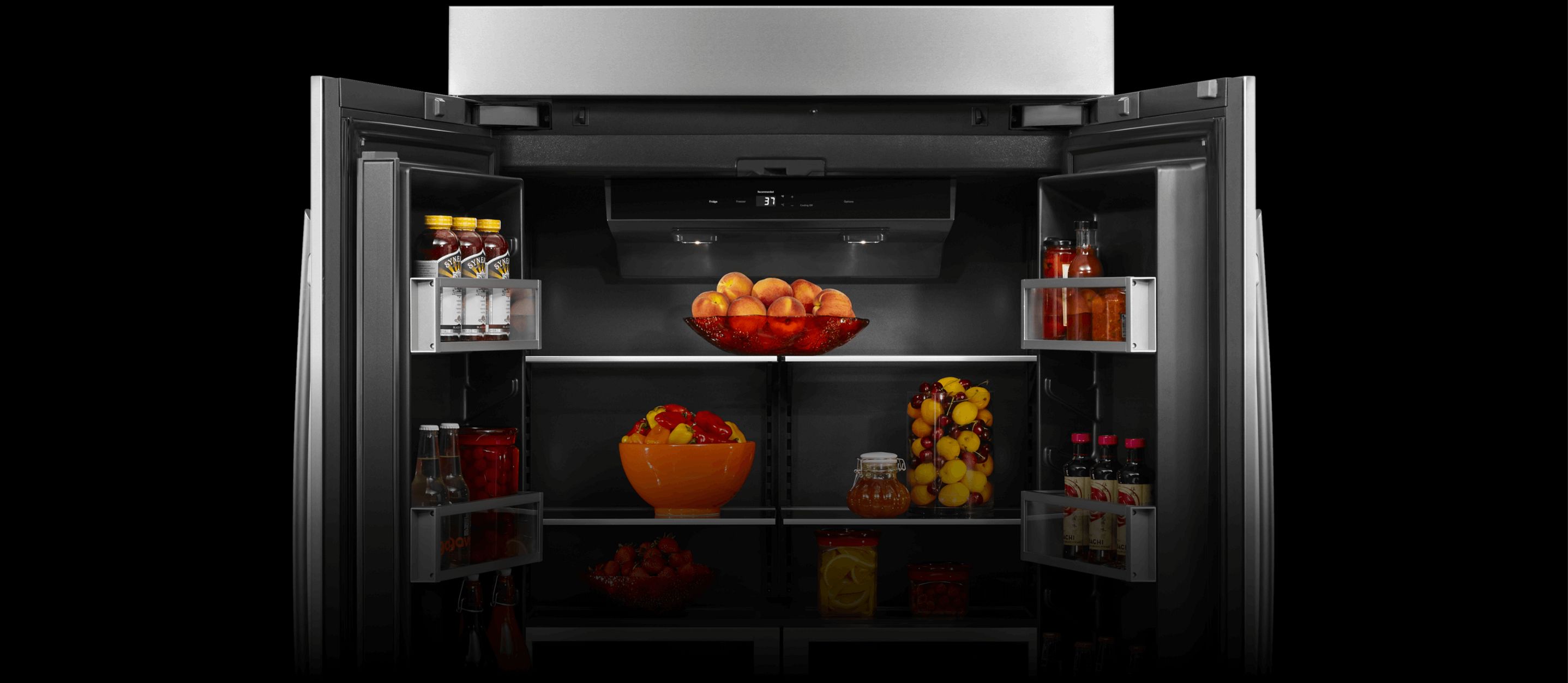 An open JennAir® high-end built-in refrigerator filled with vibrant orange fruit.