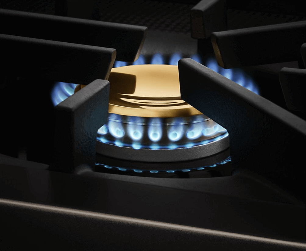 A lit brass burner on the JennAir® range.