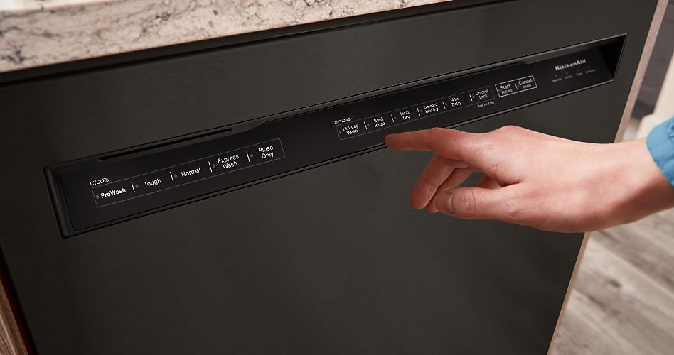Quelqu'un sur le point d'appuyer sur un bouton de lave-vaisselle KitchenAid à commandes frontales