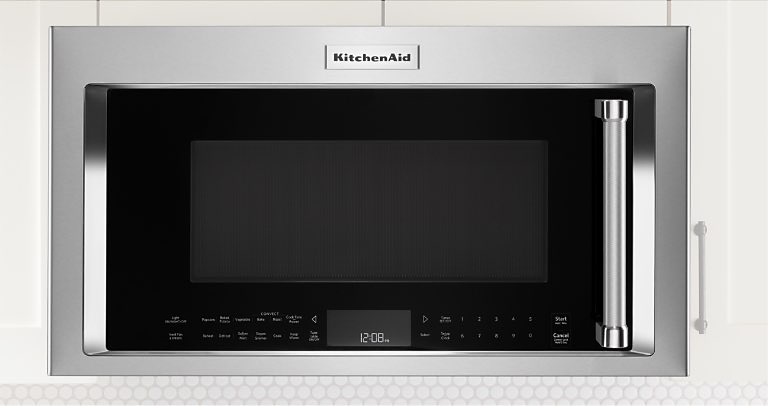 Un four à micro-ondes placé entre des armoires blanches