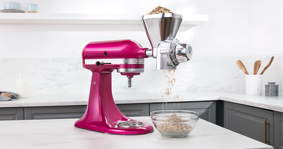 A KitchenAid Stand Mixer with a Grain Mill Attachment that is milling grain into a bowl