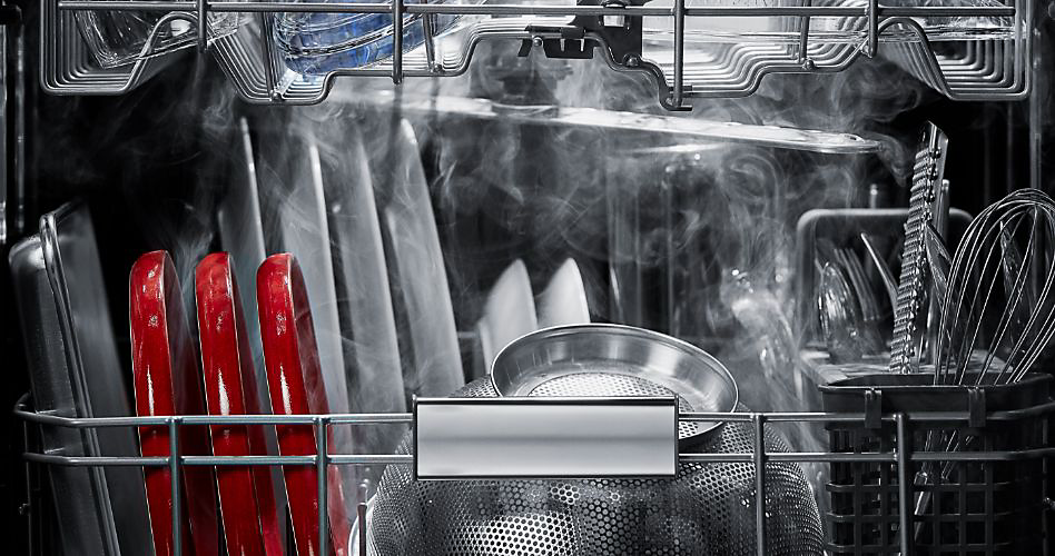 Articles dans un lave-vaisselle KitchenAid en train d'être séchés. Les articles comprennent des assiettes, une plaque à pâtisserie, des couverts, des ustensiles, des bols et des verres.