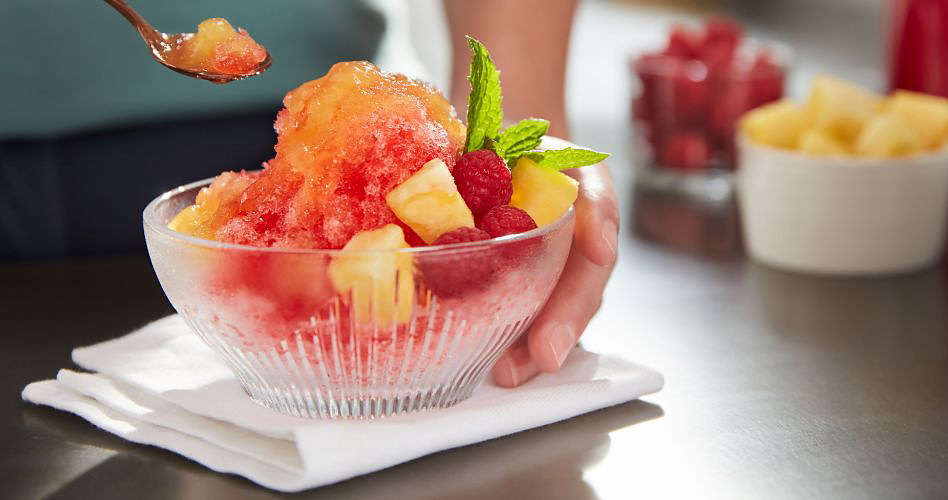 A bowl of shave ice with pineapple, mint, and raspberries