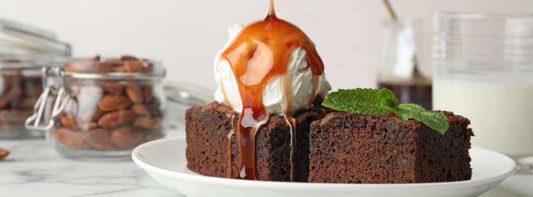  Un brownie avec une boule de crème glacée sur le dessus. Du caramel est versé sur la crème glacée et le brownie. 