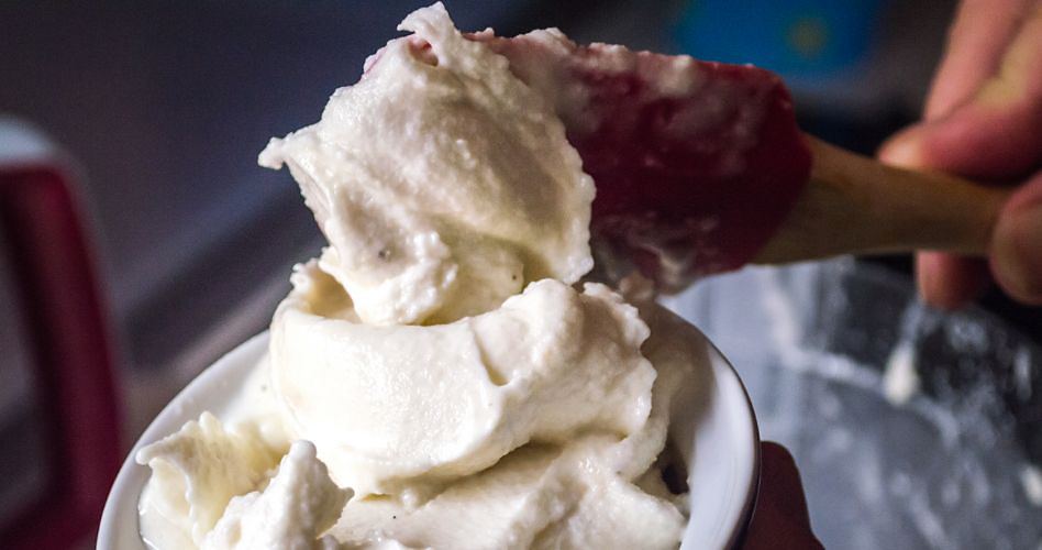De la crème glacée est versée dans un bol à l'aide d'une cuillère en bois.