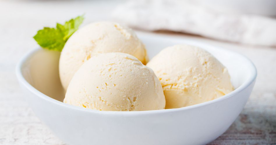 Une image montrant trois boules de crème glacée à la vanille décorée d'une feuille de menthe.