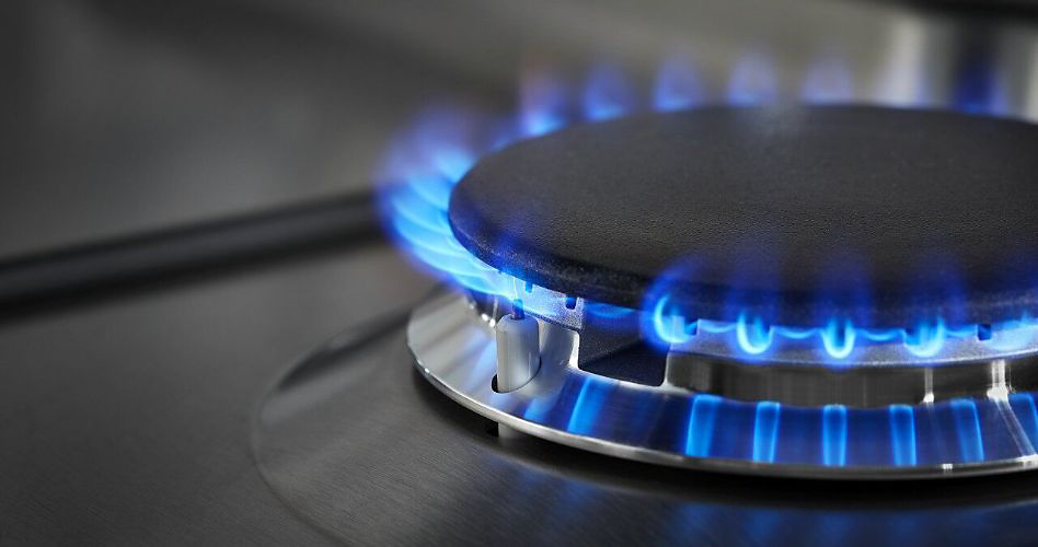 Une cuisinière au gaz avec un brûleur allumé qui émet une flamme bleue.