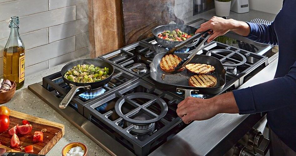 Various food items are cooked on.a gas cooktop