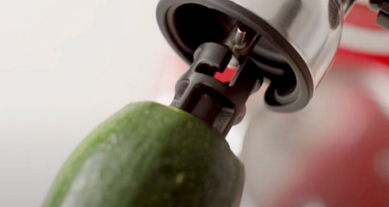 A close up of the KitchenAid Sheet Cutter Attachment being used to cut zucchini