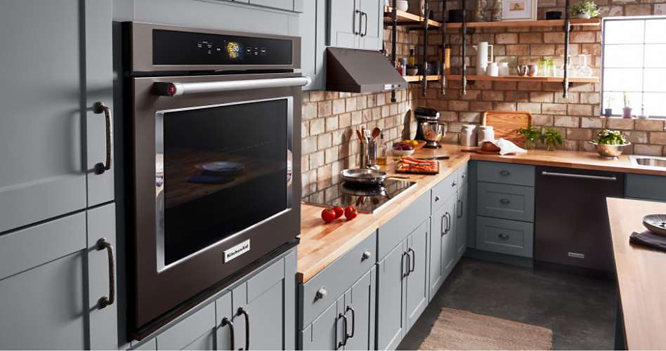 Un four mural simple KitchenAid dans une cuisine avec des armoires et comptoirs gris