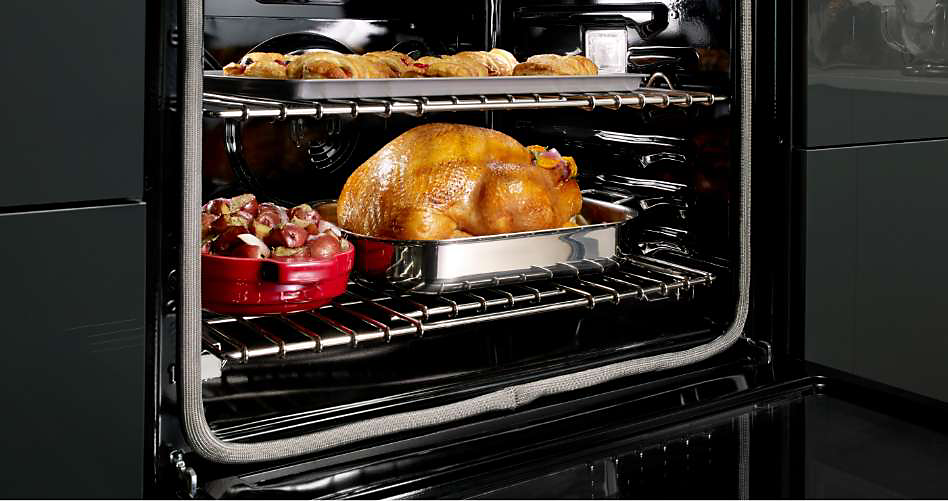 Un poulet entier et divers aliments cuisent dans un four mural KitchenAid
