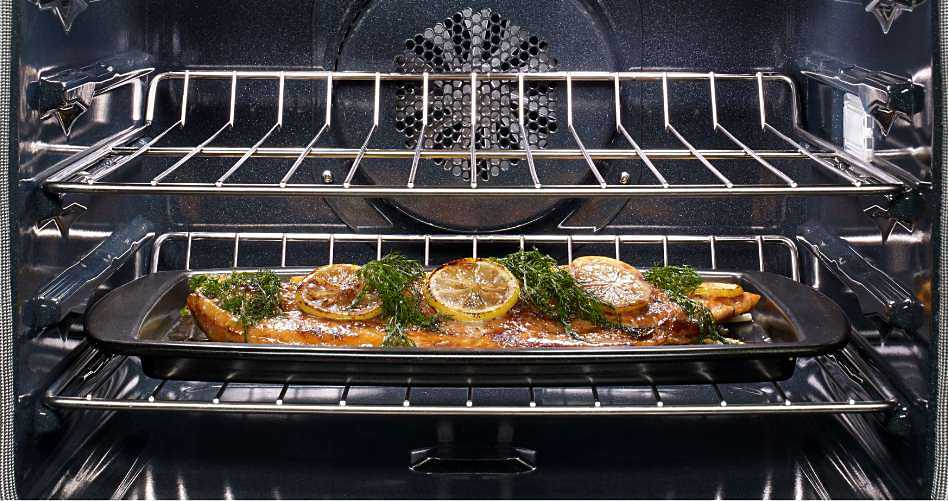 Un poisson avec du citron et des herbes fraîches cuisent dans un four mural KitchenAid