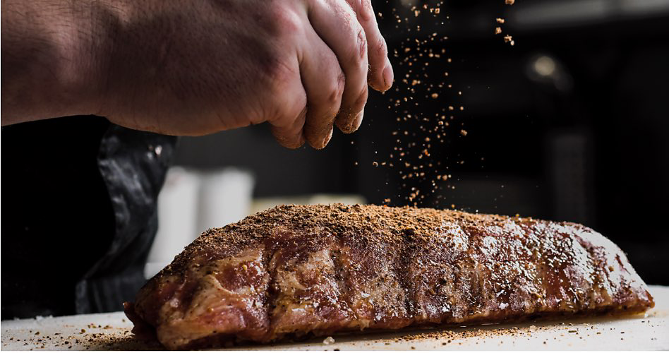 Quelqu'un qui assaisonne le poulet sur une planche à découper