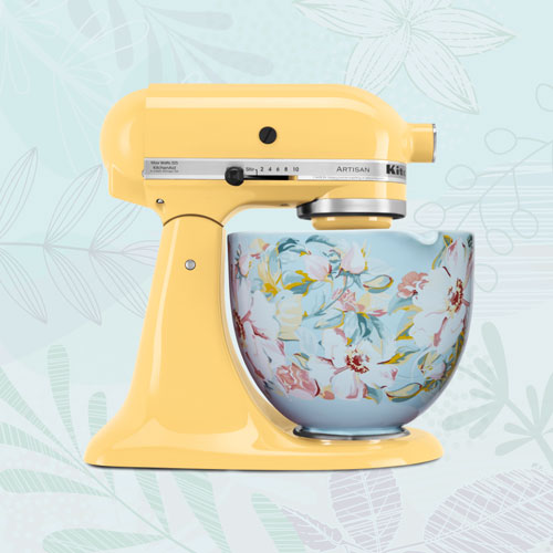 Yellow Stand Mixer with floral textured bowl in fornt of light blue textured background