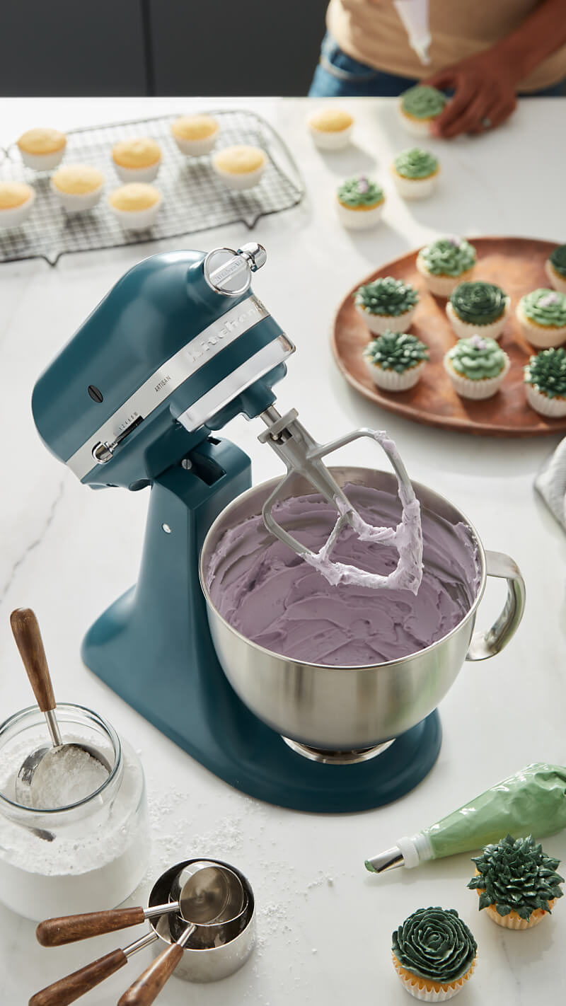 An Agave Stand Mixer mixing up frosting, surrounded by cupcake baking materials.