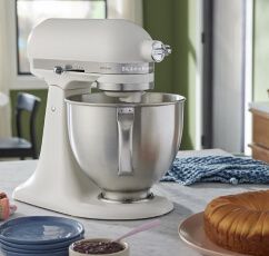 A KitchenAid® Porcelain White Stand Mixer on a countertop next to prepared braided bread.