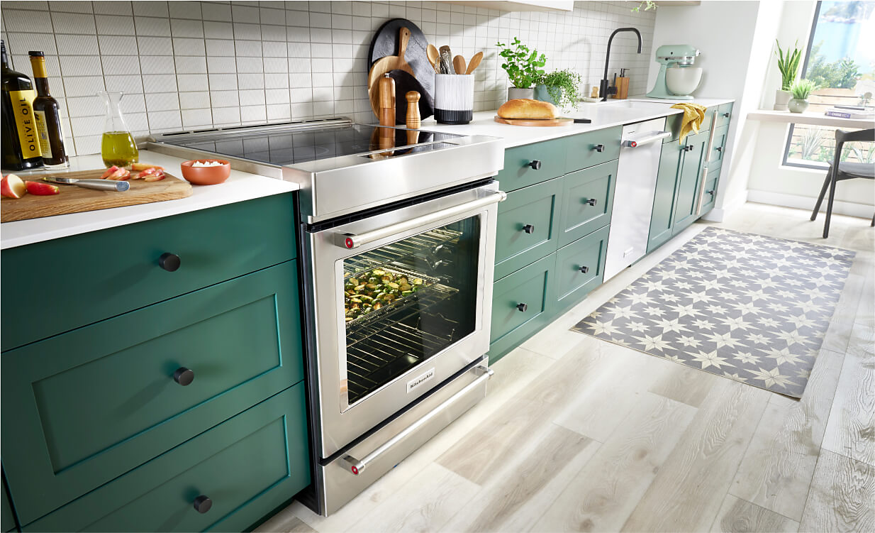 A KitchenAid® Slide-In Range in a kitchen with bold green cabinets.