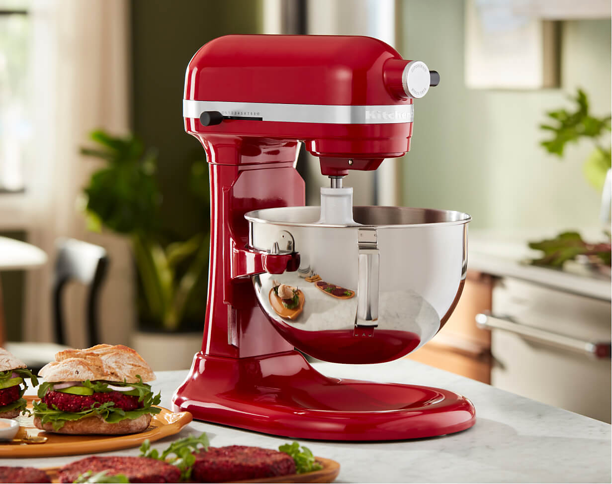 A KitchenAid® Bowl-Lift Stand Mixer in Empire Red on a countertop near prepared beetroot burgers.