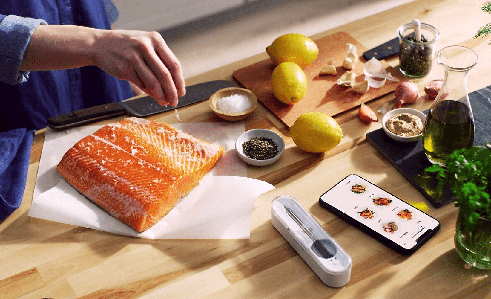 A person sprinkling flaky sea salt over a salmon filet, following a recipe from Yummly and using the Yummly Smart Thermometer.