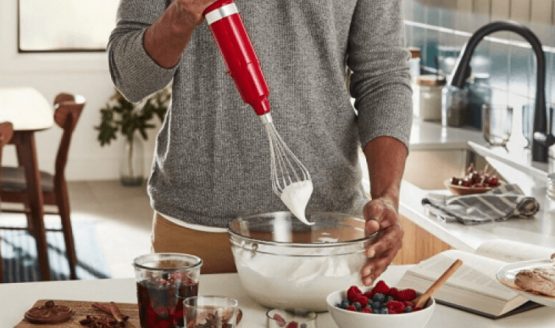 A man whisking a bowl of whipped cream.