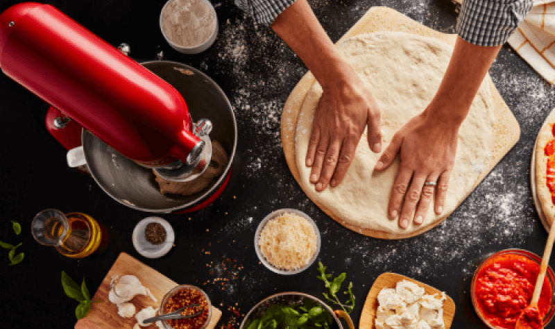 A person spreading pizza dough on a pizza stone.