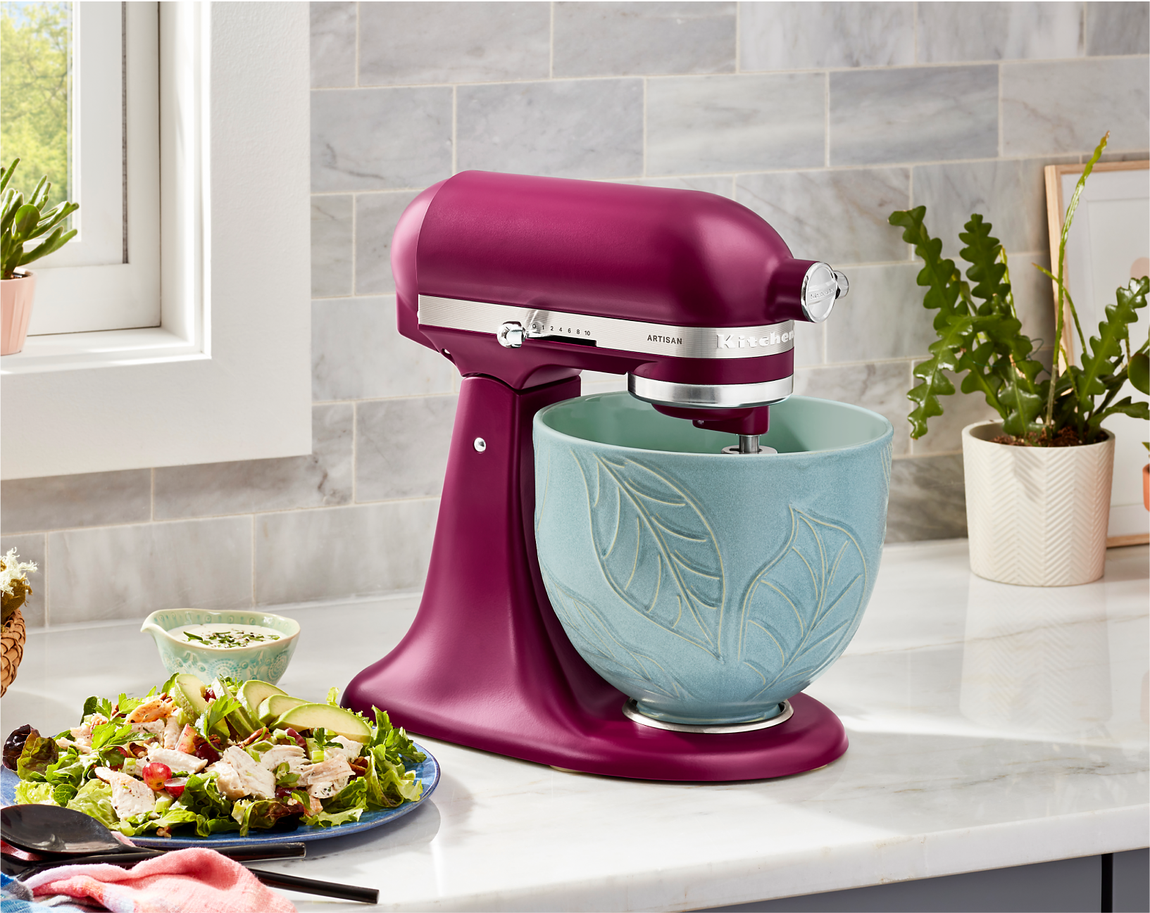 A KitchenAid® Stand Mixer in Beetroot on a countertop using an embossed blue bowl.