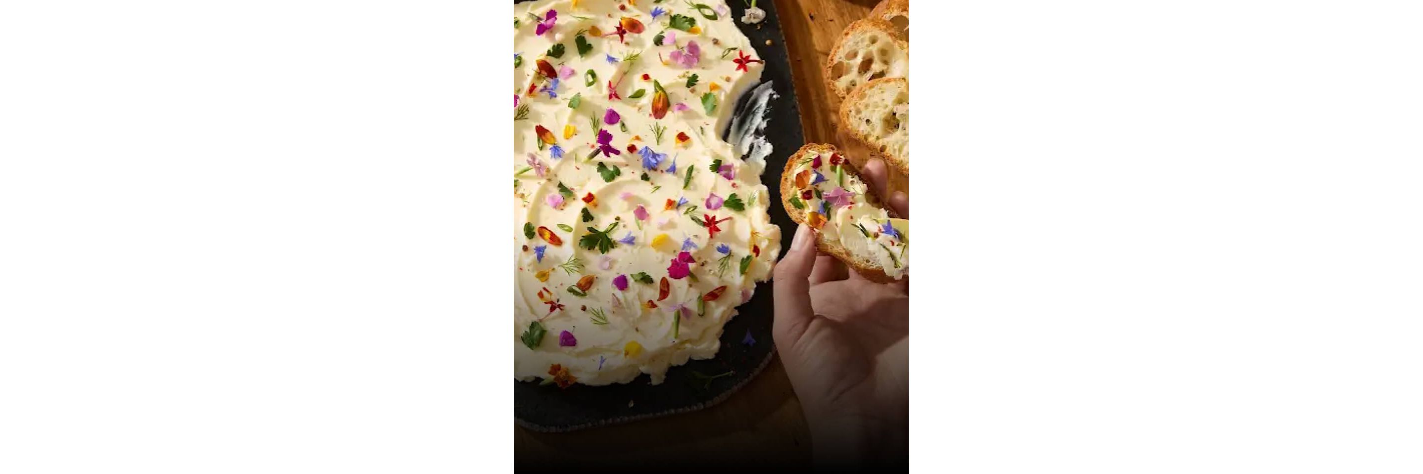 A butter board garnished with edible flowers and herbs. 