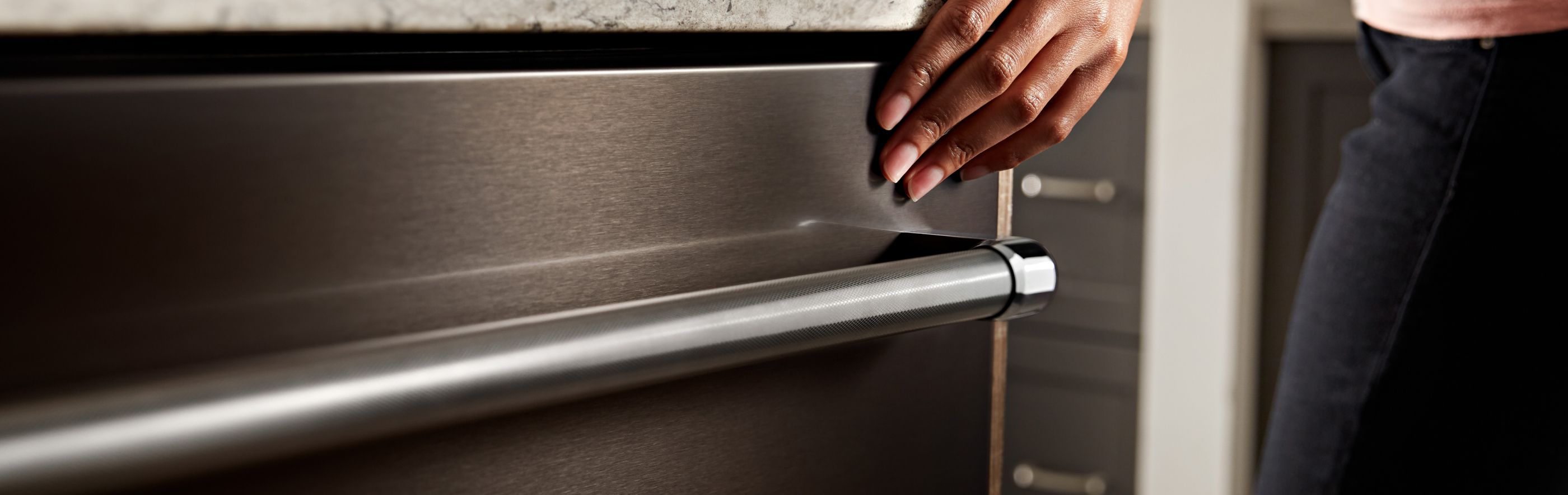 Hand closing a stainless steel dishwasher