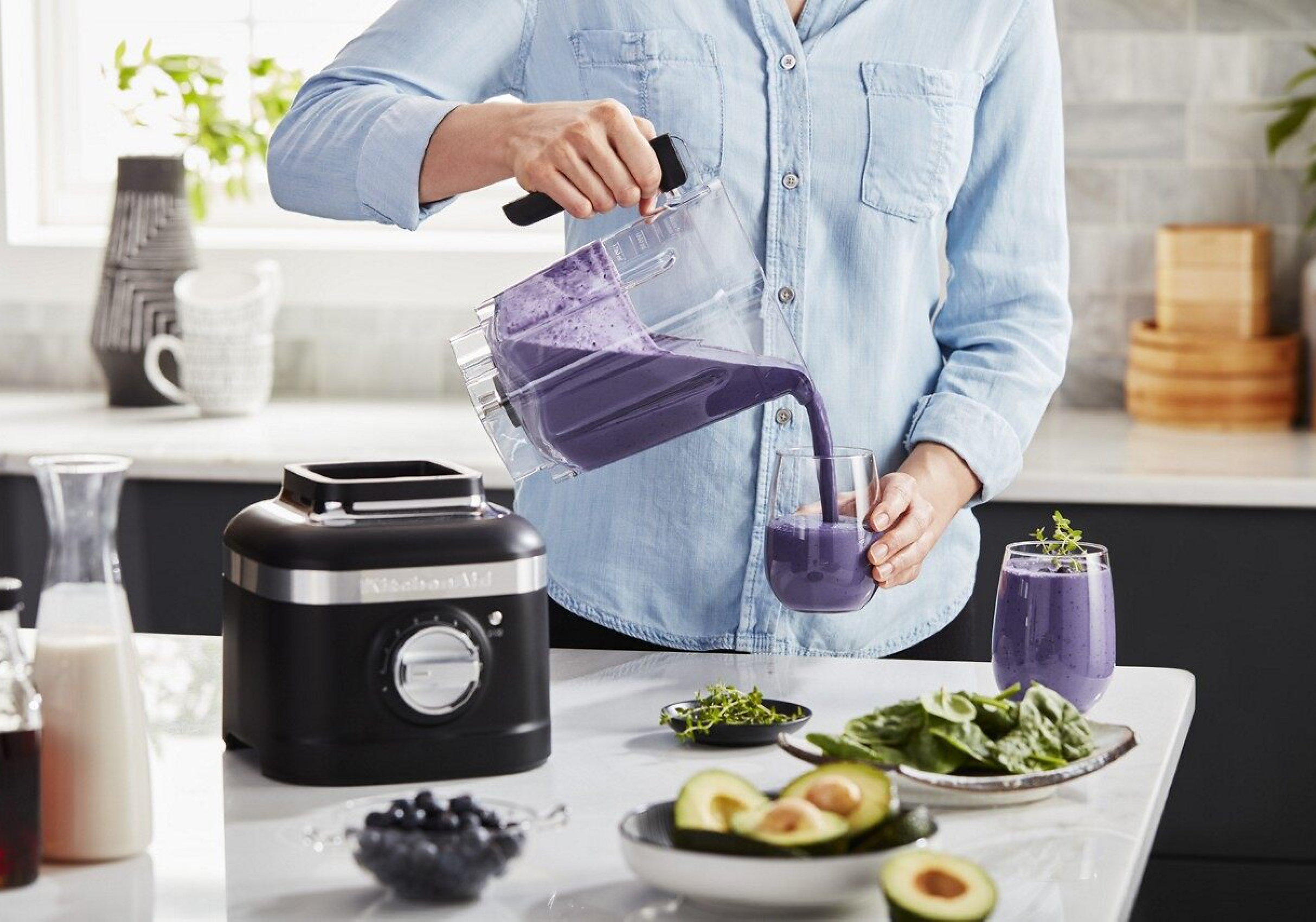 A person pouring a purple smoothie from a KitchenAid® blender.