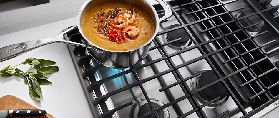 Seafood bisque cooking on a downdraft gas cooktop