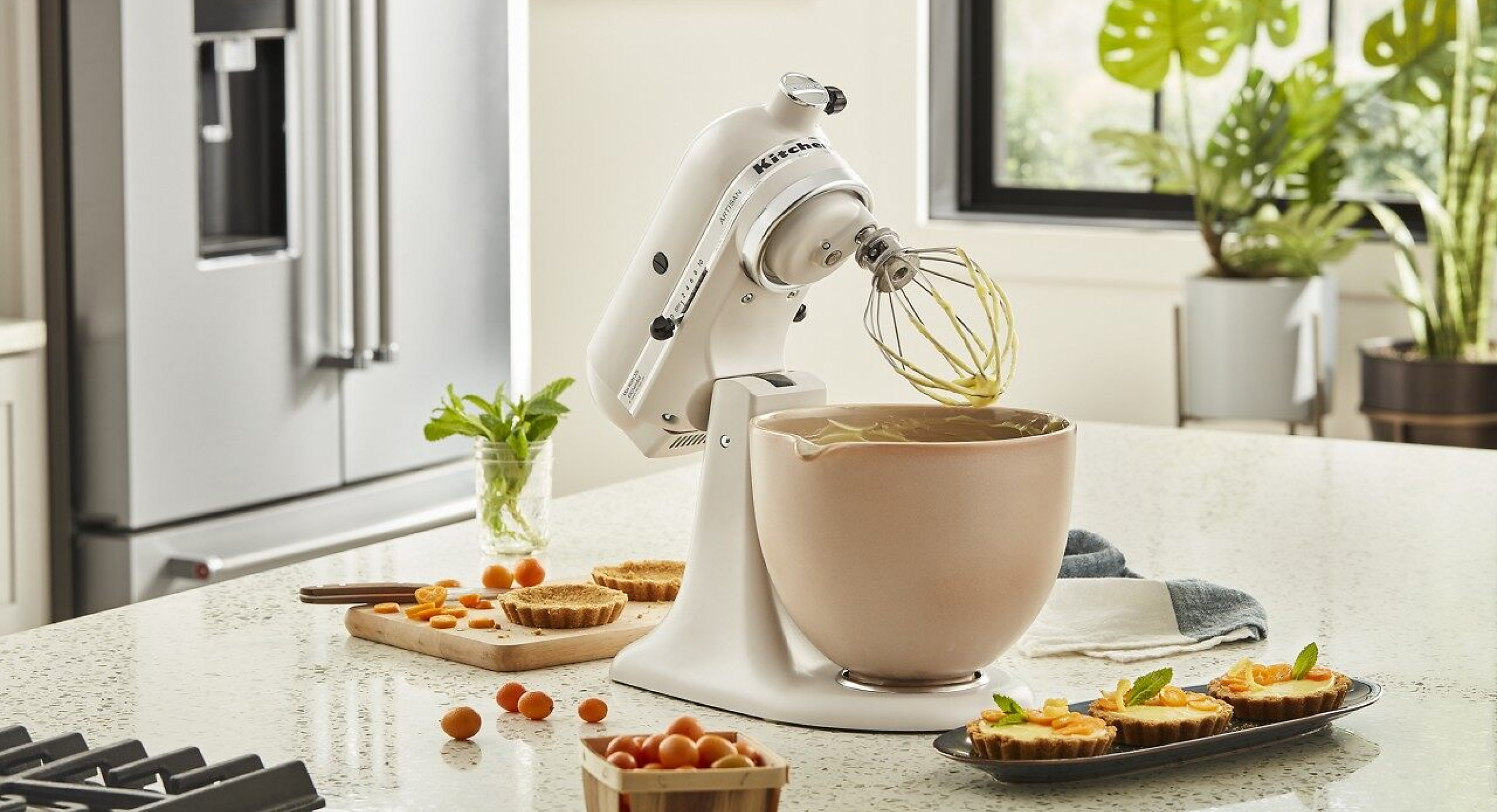 A white stand mixer on a kitchen island with baking ingredients