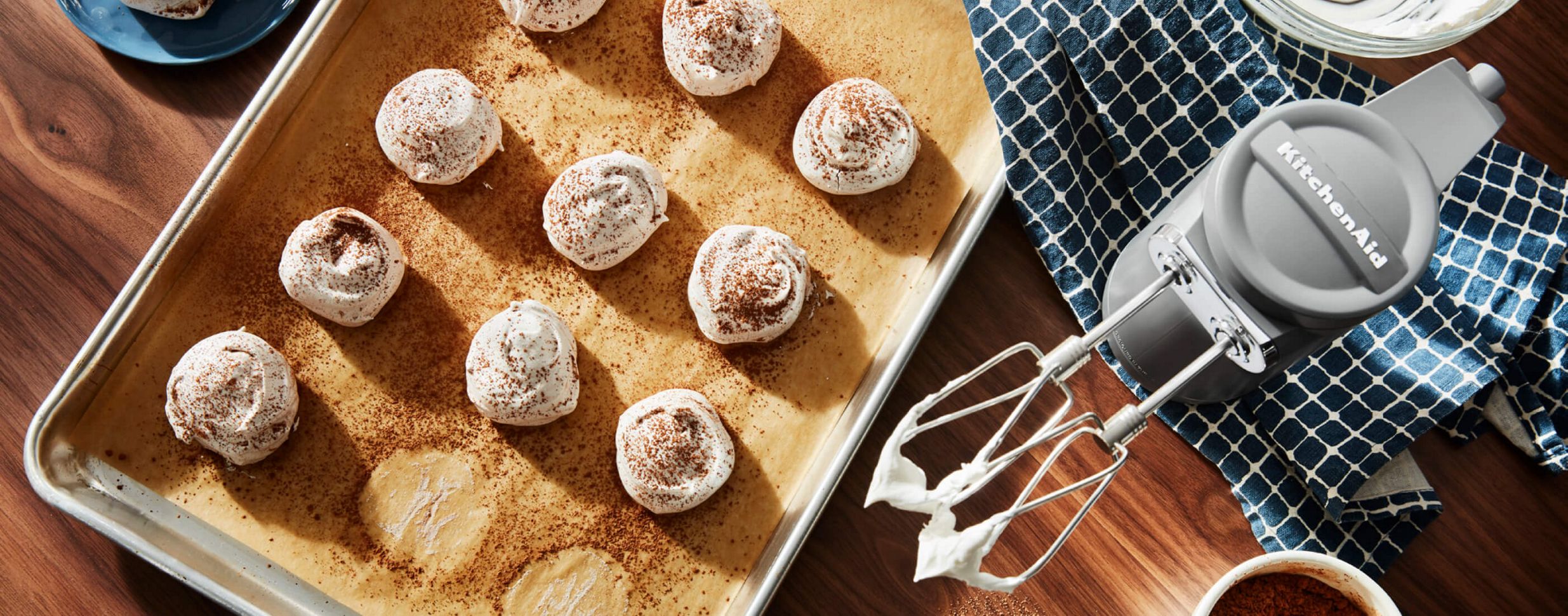 Freshly-made meringues resting on parchment paper in a baking sheet.
