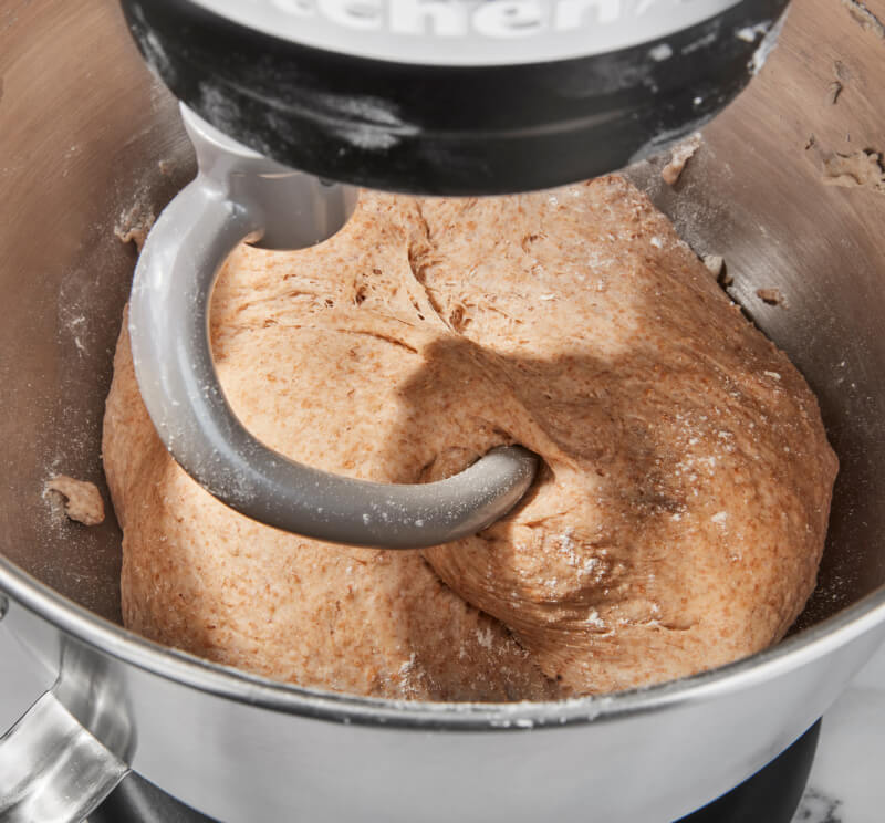 The interior of KitchenAid® bowl-lift stand mixer using a dough hook to mix dough. 