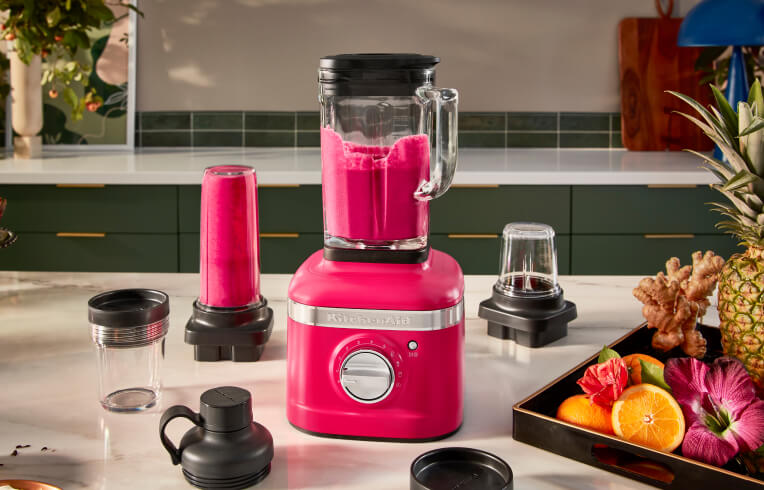 A K400 Blender in Hibiscus blending a bold pink beverage with different attachments.